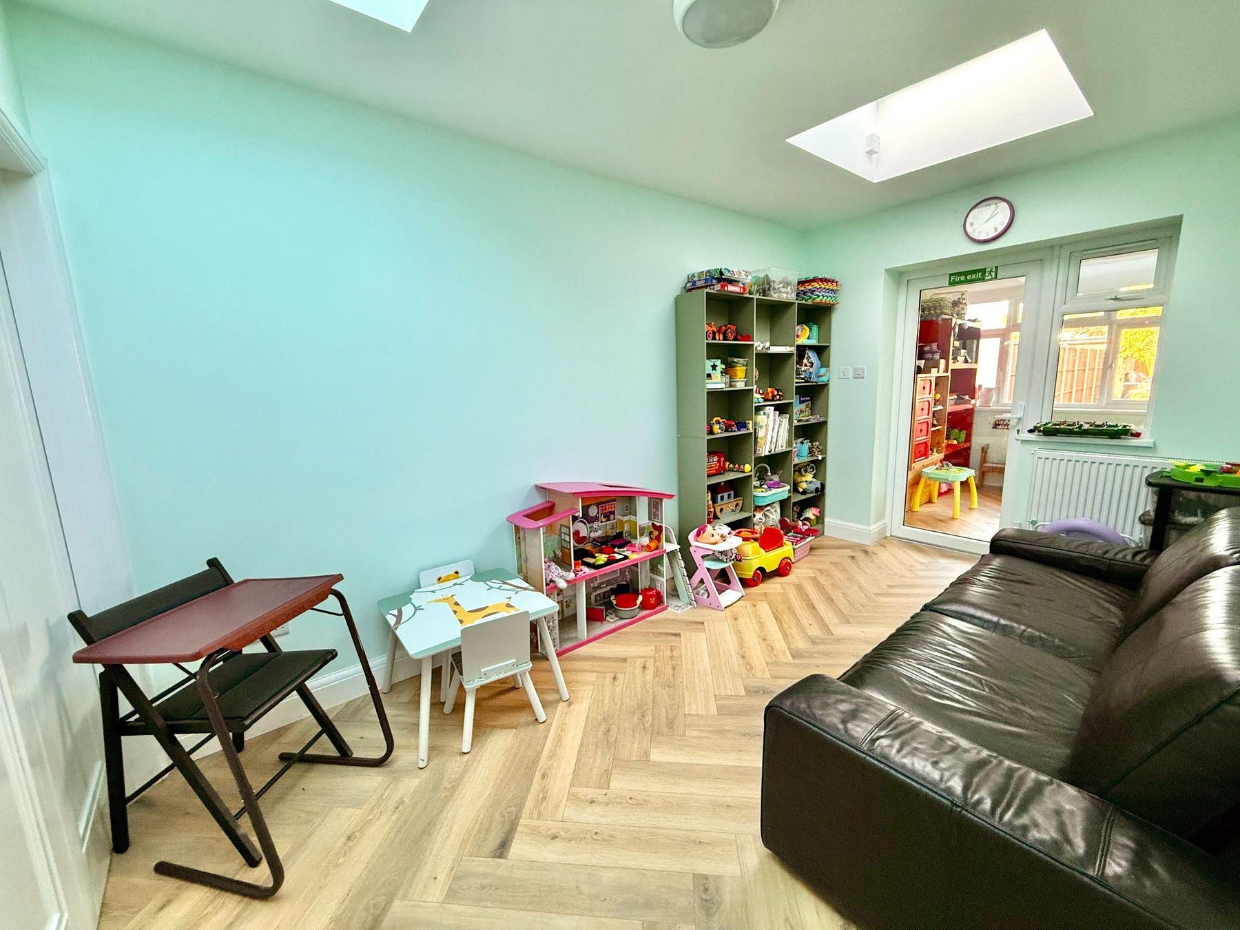 Room with dolls' house, toy shelves and leather sofa