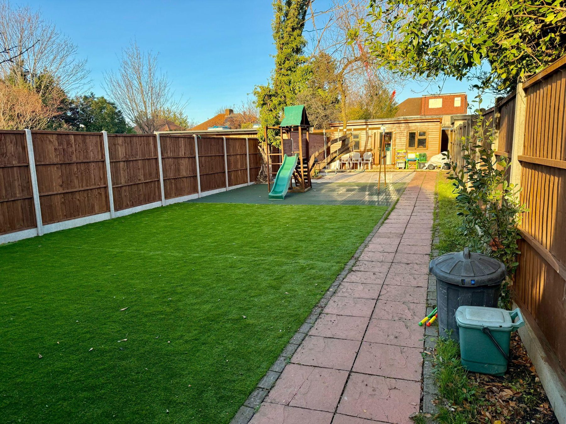Enclosed rear garden with lawn, path and climbing frame