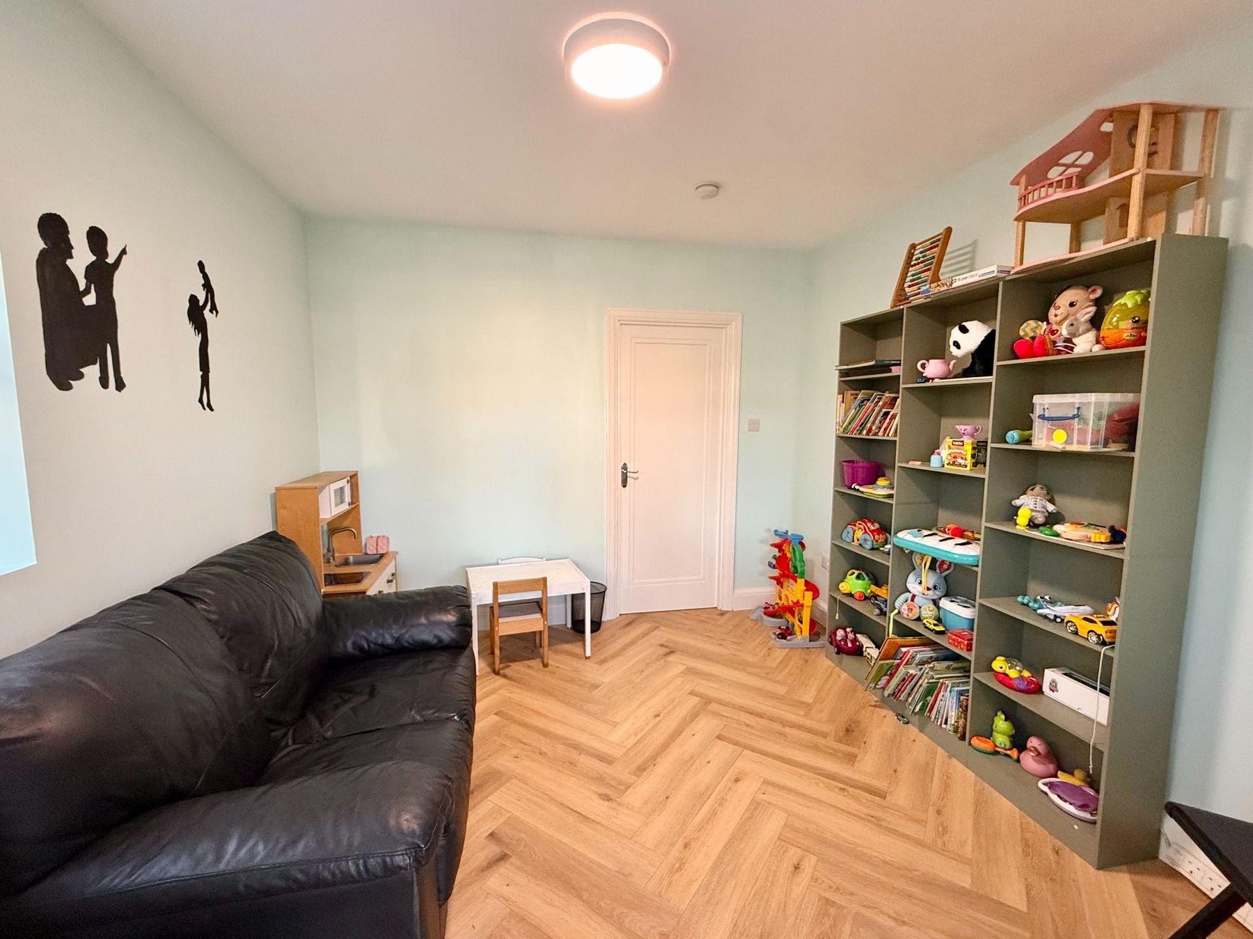 Room with dark sofa, wooden play kitchen and toy shelves
