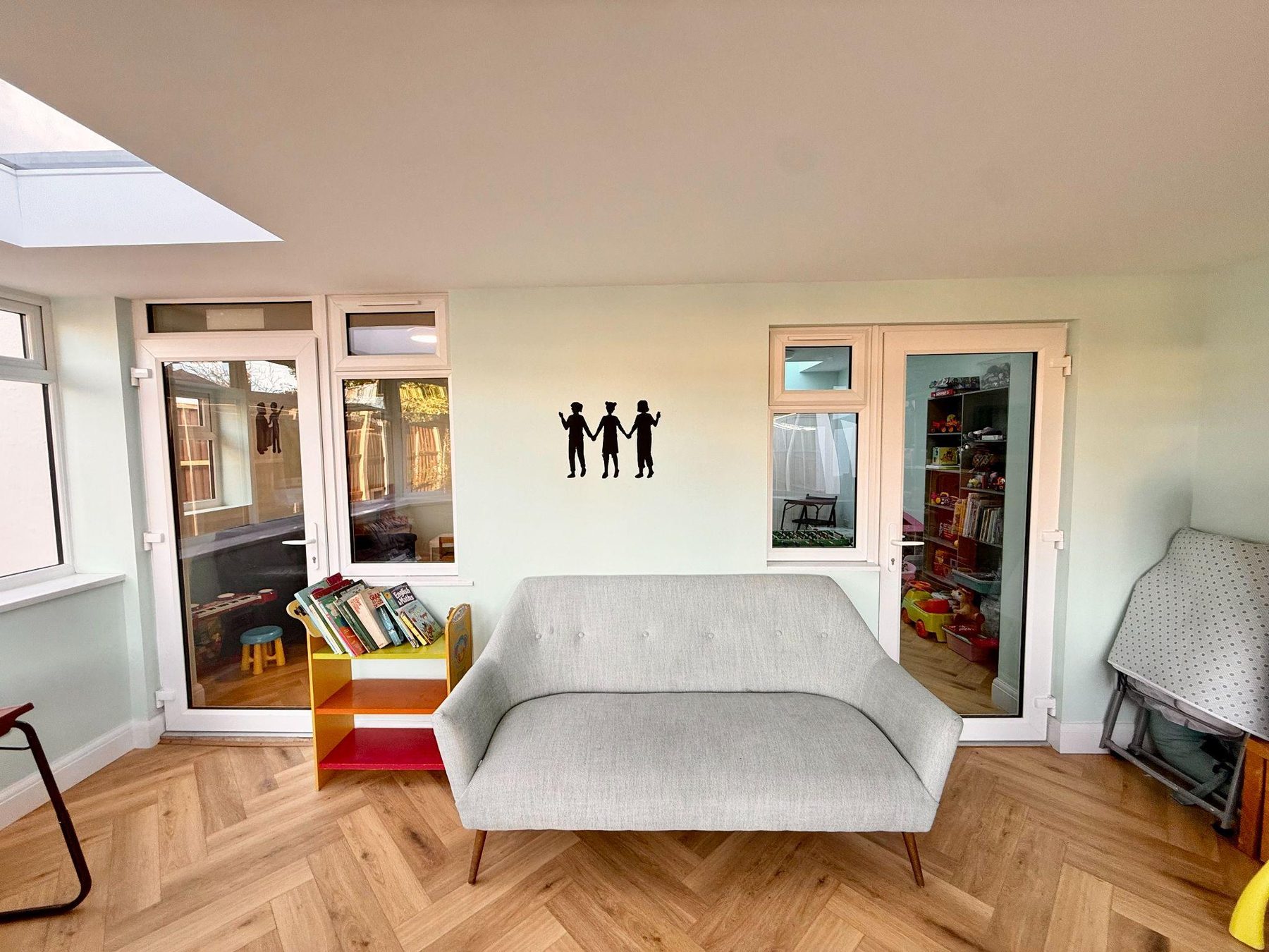 Garden room with grey sofa, book display and skylight