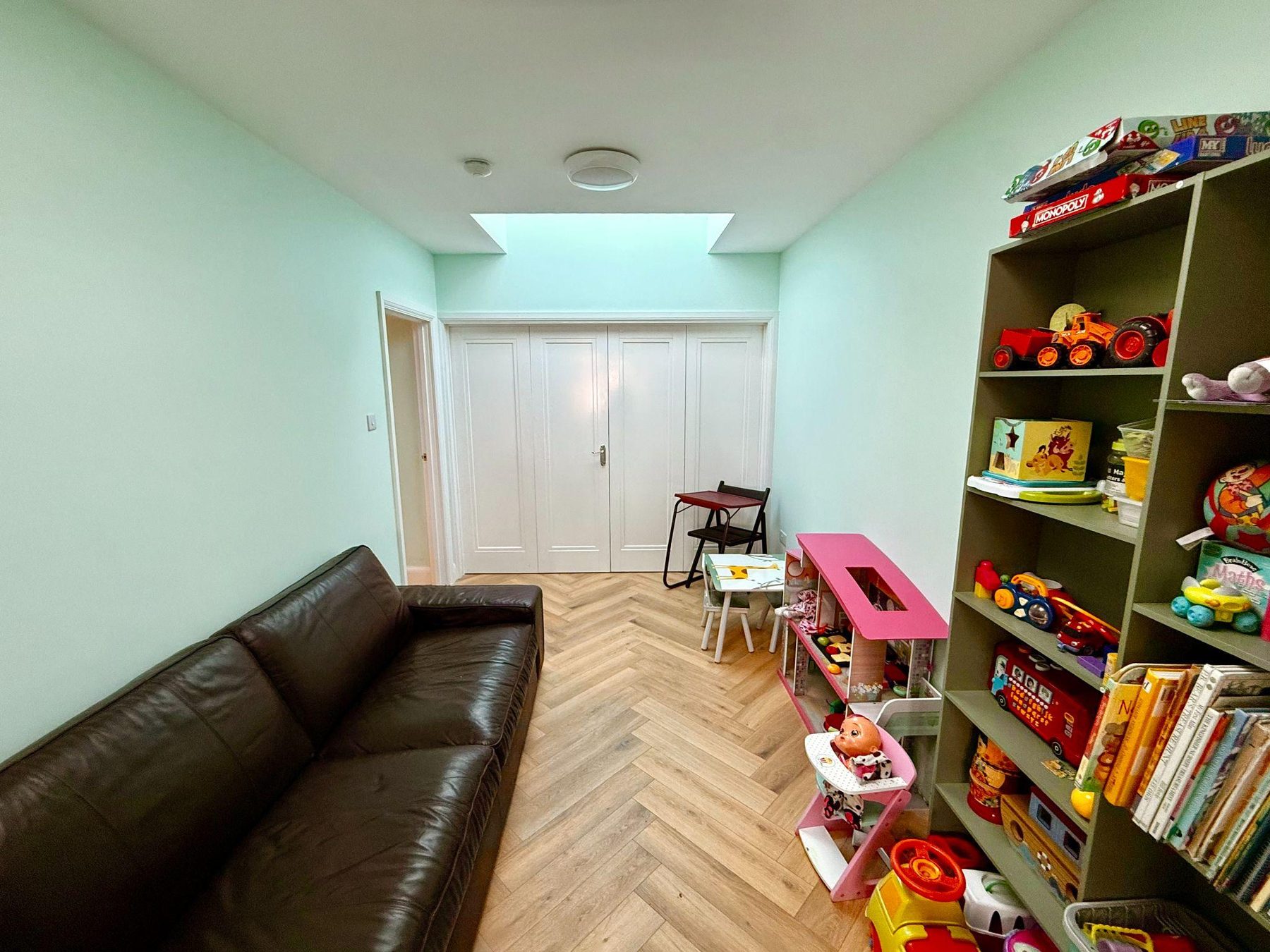 Long room with sofa, toy shelves and double doors