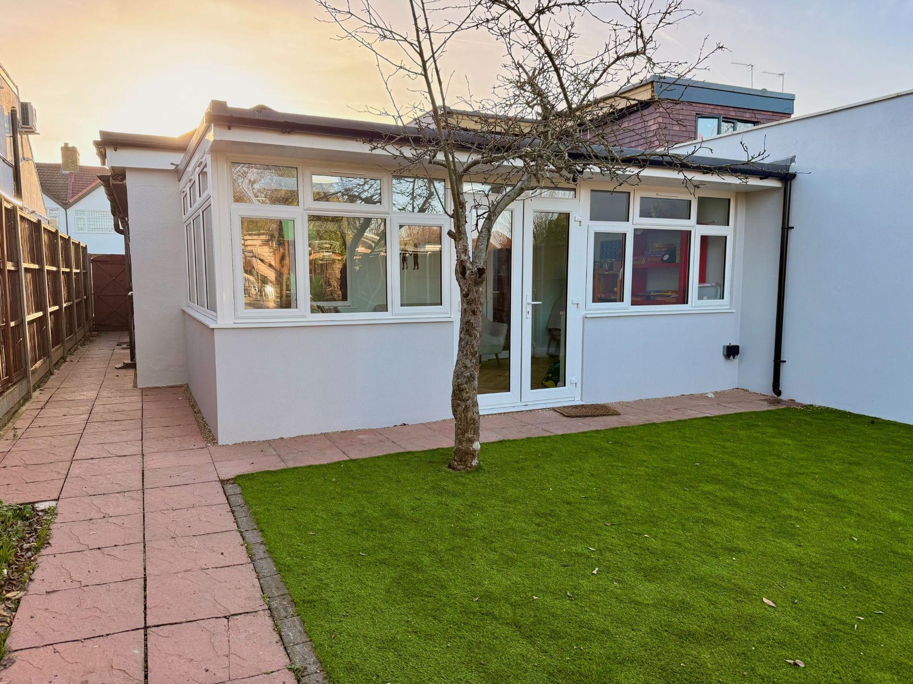 Rear of the building with conservatory, lawn and paved path