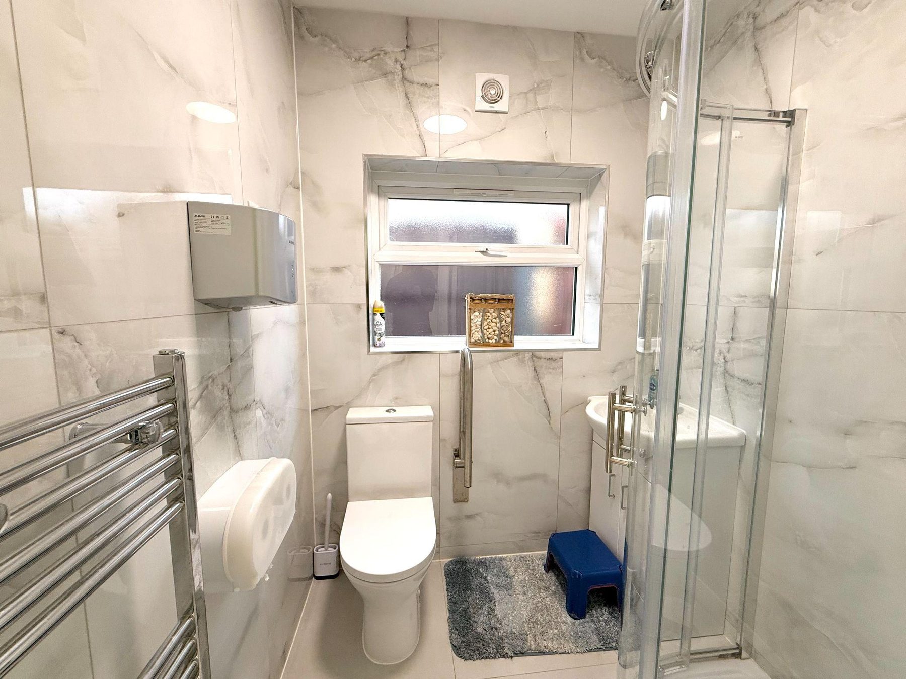 Tiled shower room with toilet, basin and child step stool