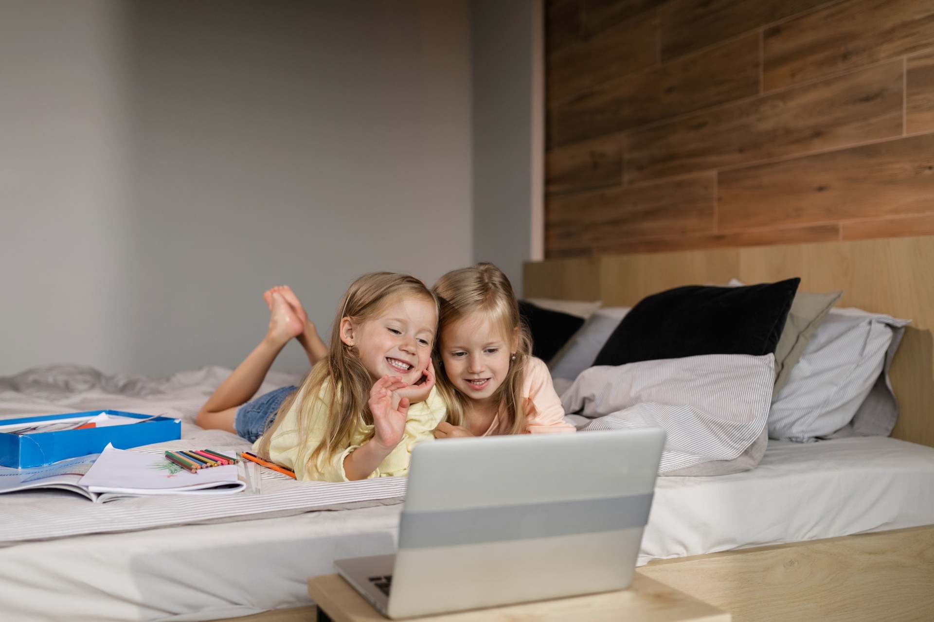 Two young siblings smiling while using a laptop together at home