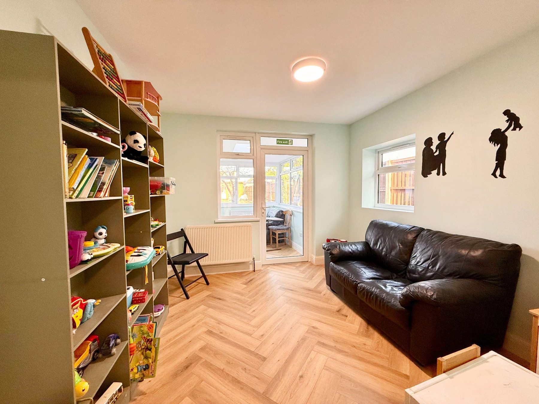 Room with tall bookcase, sofa and doors to a rear room