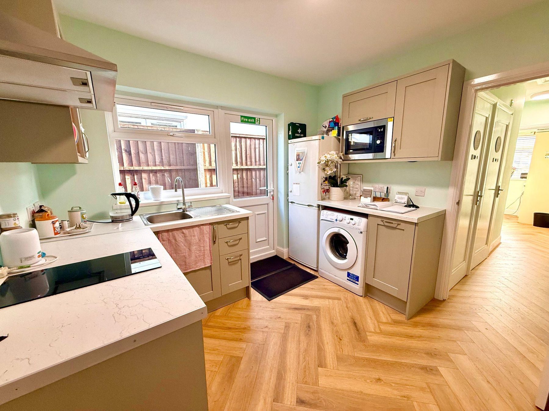 Kitchen with cream units, washing machine, fridge and microwave
