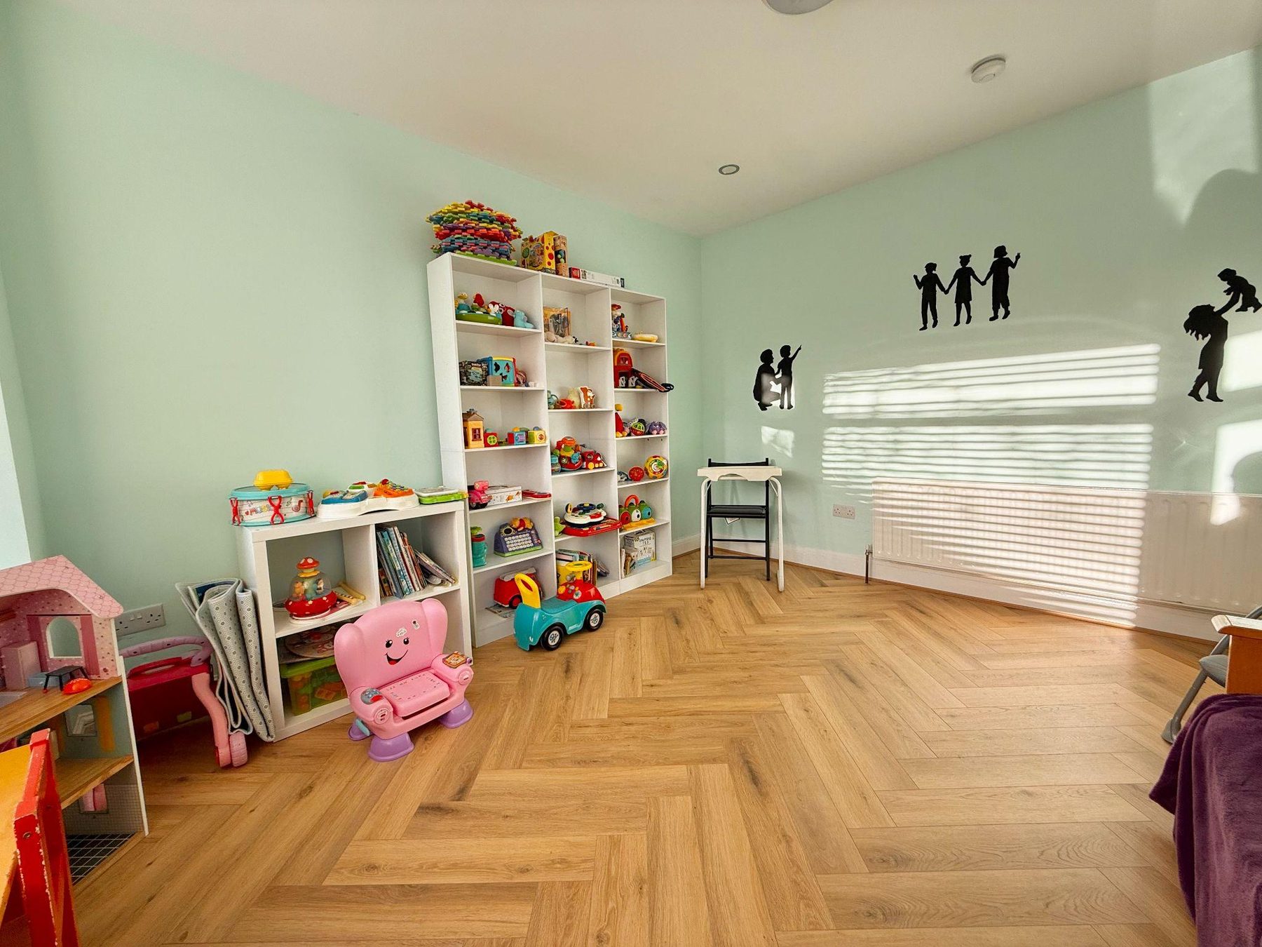 Play room with toy storage shelves and child silhouette wall stickers