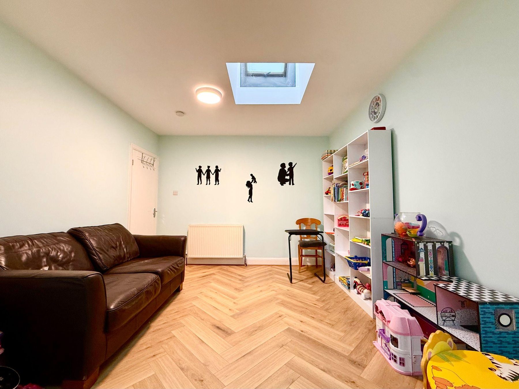 Room with leather sofa, skylight, high chair and toy shelving