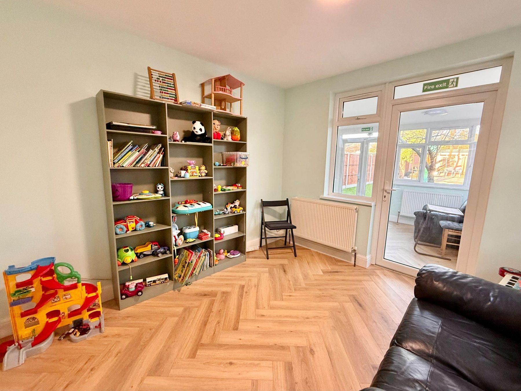 Room with toy and book shelving and glazed doors to the garden